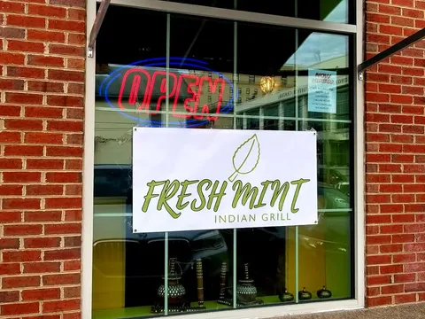 Storefront window of Fresh Mint Indian Grill at 40 High Street, Morgantown, with the restaurant's leaf-logo banner and a red-and-blue neon OPEN sign in the glass