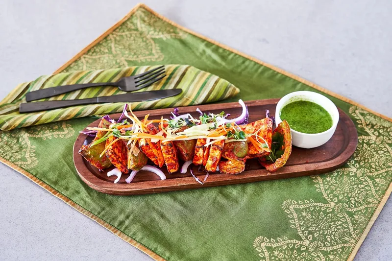 Paneer tikka skewers with green chutney on a wooden platter at Simha Indian Kitchen & Bar in downtown Providence