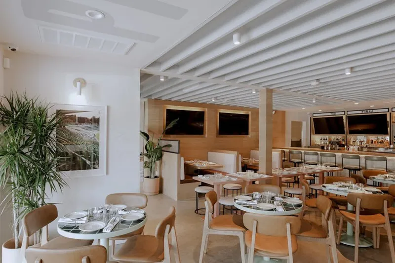Bright Pijja Palace dining room with round set tables, wood chairs, and a long bar