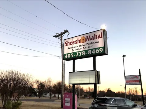 Roadside sign for Sheesh Mahal reading 'Authentic Halal Pakistani & Indian Cuisine' with the phone number 405-778-8469, on N May Ave in Oklahoma City