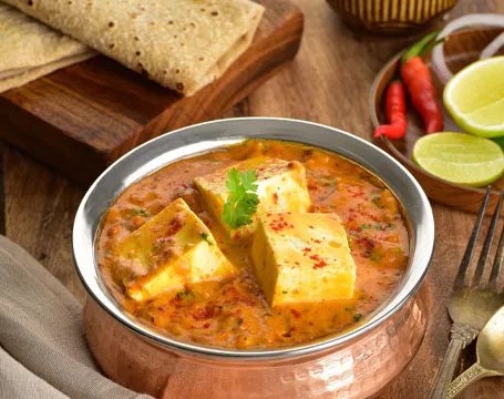 Copper serving bowl of paneer curry garnished with cilantro, served with roti, at Hyderabad House in Louisville