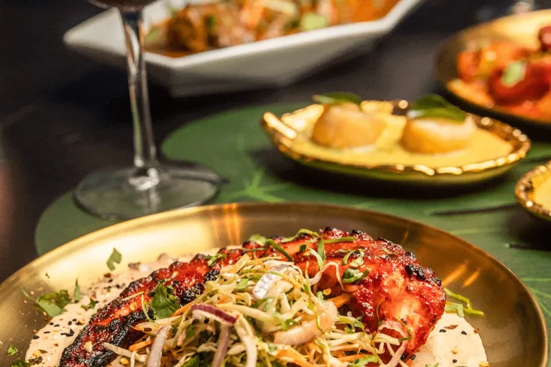 Tandoori octopus plated with slaw on a gold thali, with scallops and sangria, at Moksha Indian Brasserie in Fort Lauderdale