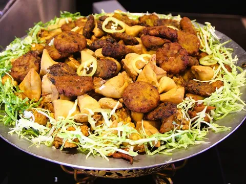 A large steel platter of assorted fried Indian appetizers — samosas, pakoras and fritters garnished with shredded cabbage and green chilies — at Taj Mahal Indian Cuisine in Pittsburgh