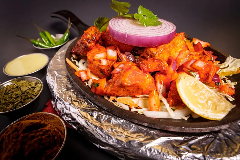 Sizzling tandoori mixed grill of chicken tikka and kebabs topped with a grilled onion ring, with chutneys and spices alongside, at Maharaja Indian Cuisine in Omaha