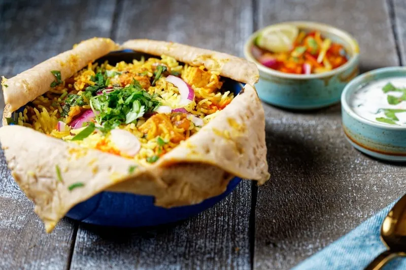 Dum biryani sealed with roti, served with raita and salan at Nirmanz Food Boutique