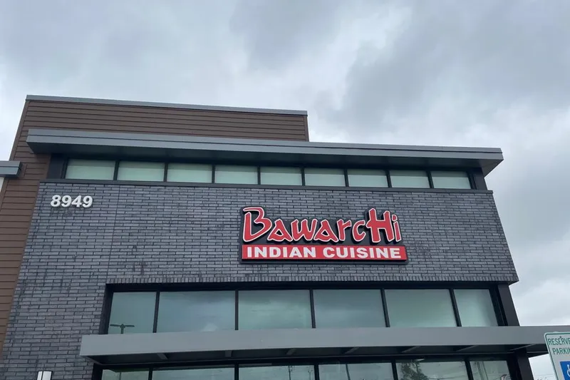 Exterior of Bawarchi Indian Cuisine (East Frisco) — a grey-brick two-story building with a red 'BawarcHi Indian Cuisine' sign and the address number 8949 — in Frisco, Texas