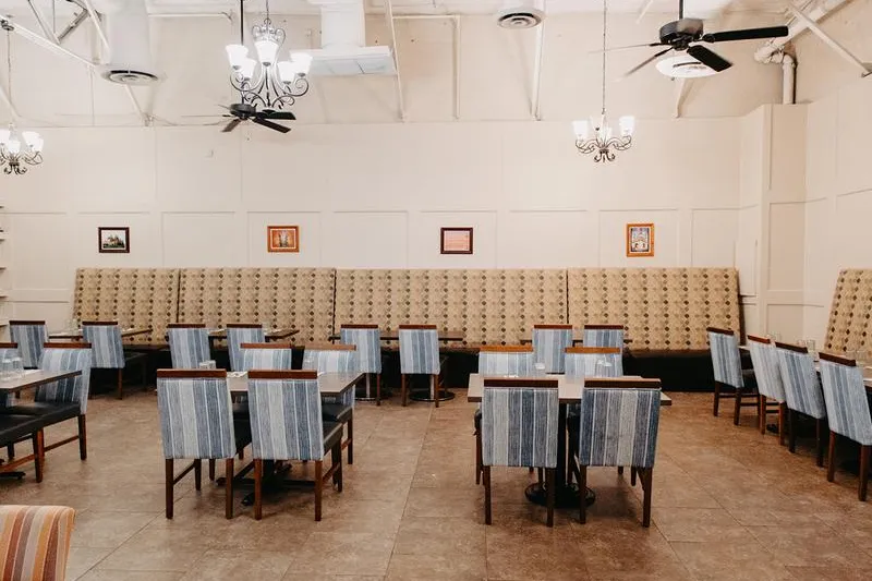 Dining room with banquette seating, striped chairs and chandeliers at India Oven