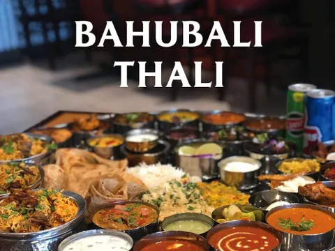 Overhead of Godavari's Bahubali Thali, a large shared platter of biryanis, curries, breads and accompaniments, promotional photo from Godavari in Edison, New Jersey