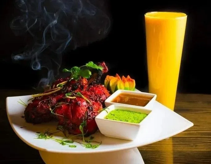 Tandoori chicken garnished with cilantro, served with mint and tamarind chutneys and a mango lassi at Pakeezah in Bozeman