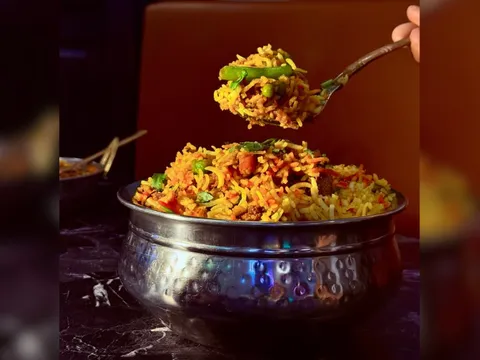 Biryani served in a hammered steel bowl with a spoonful lifted above it, at Panj Tara in Allen